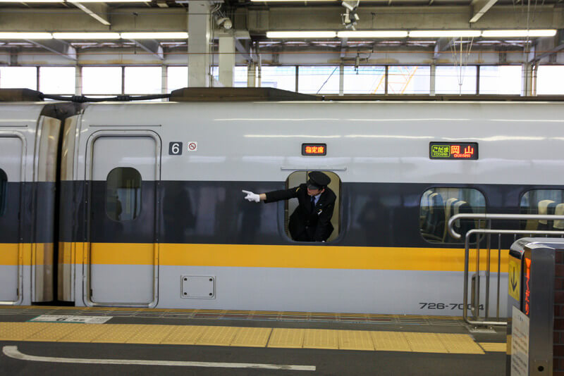 A Hiroshima train conductor pointing along the track