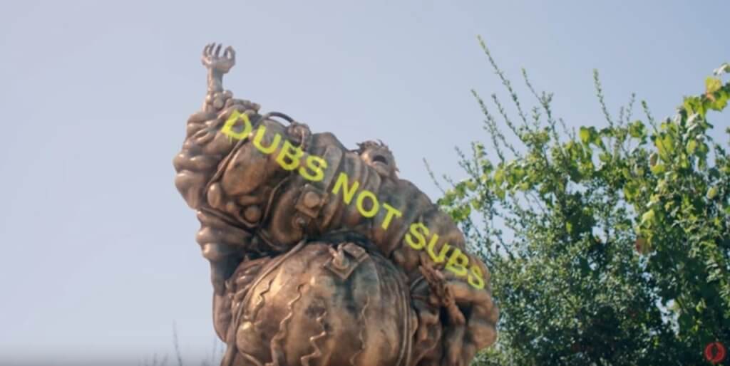 A screenshot of a statue with "Dubs not subs" written in graffiti