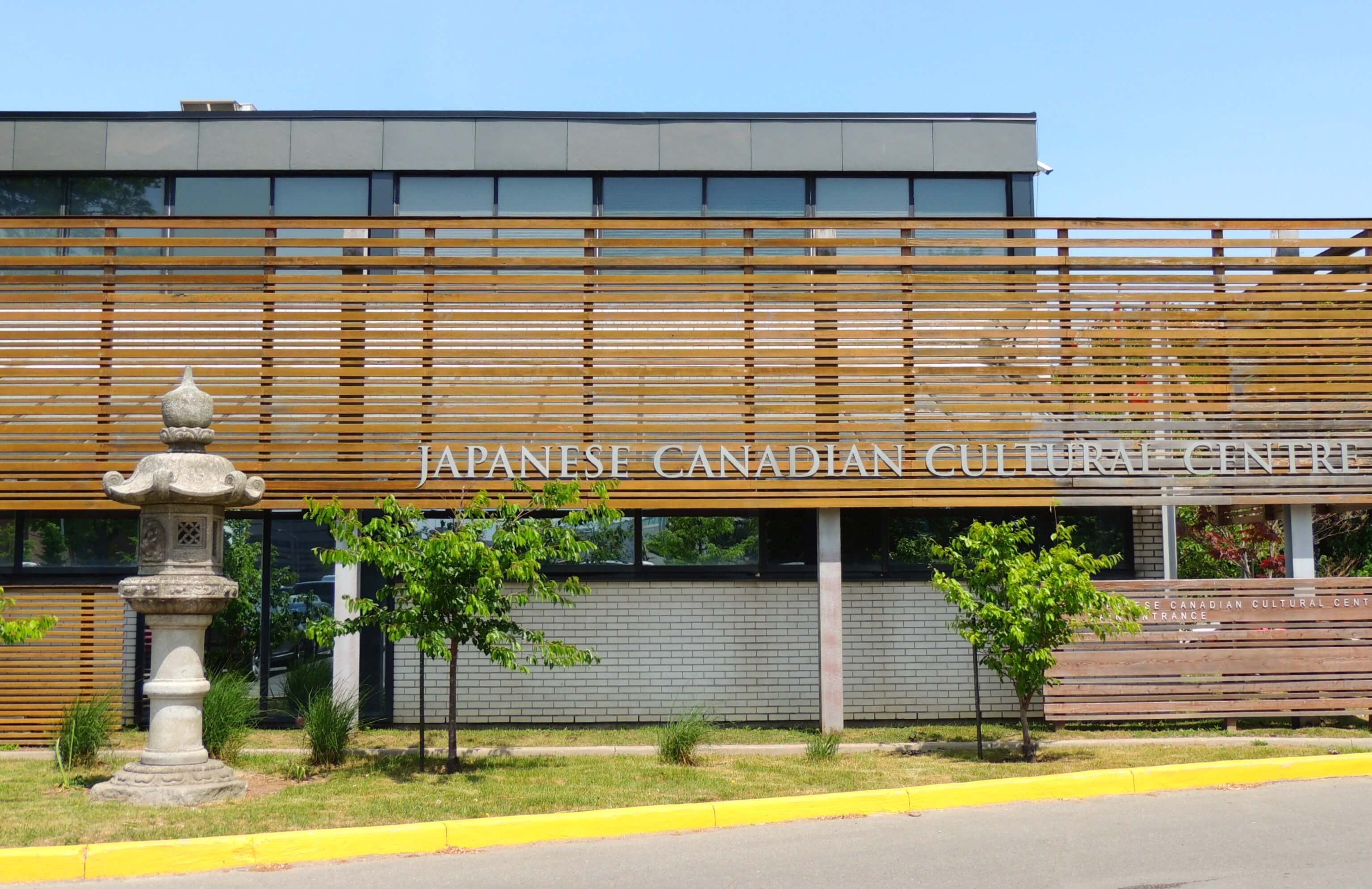 Exterior of the Japanese Canadian Culture Center in Toronto with a Japanese stone statue at the front of the building.