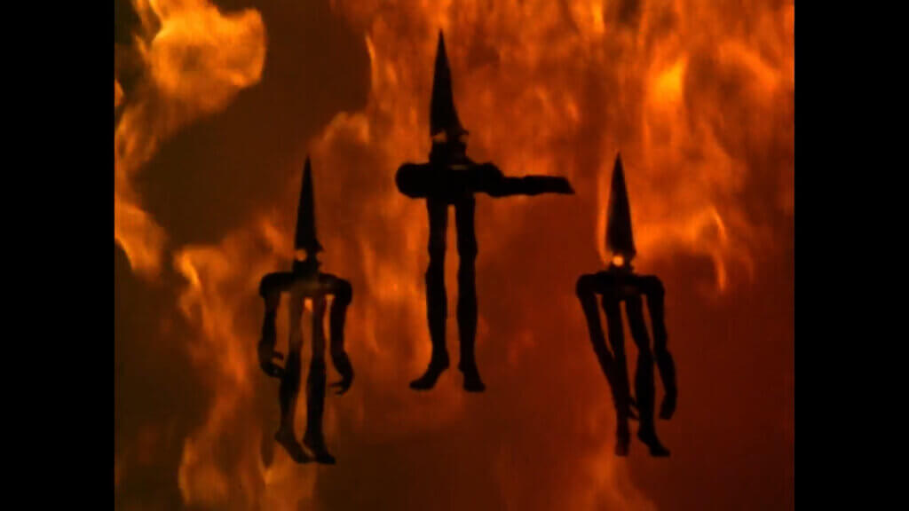 In an episode of ultraseven, black silhouettes of pointy-headed aliens with long arms and legs and bulbous eyes hang from the air against a background of red fire.