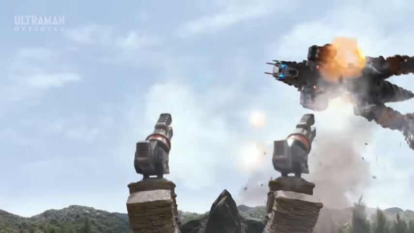 In ultraman blazar, a large kaiju-shaped robot called "earth garon" jumps from the side, guns blazing, while facing off against a gun-mounted kaiju. behind them is the blue sky and anonymous forested hills.