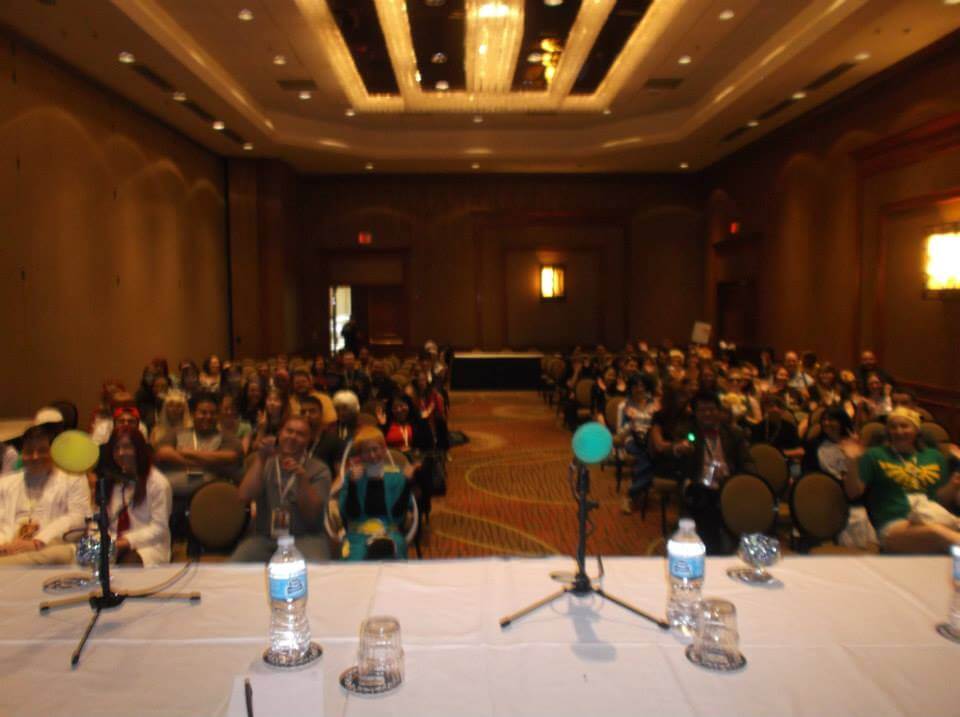 A dim lit panel room in the Sheraton with lots of people in it