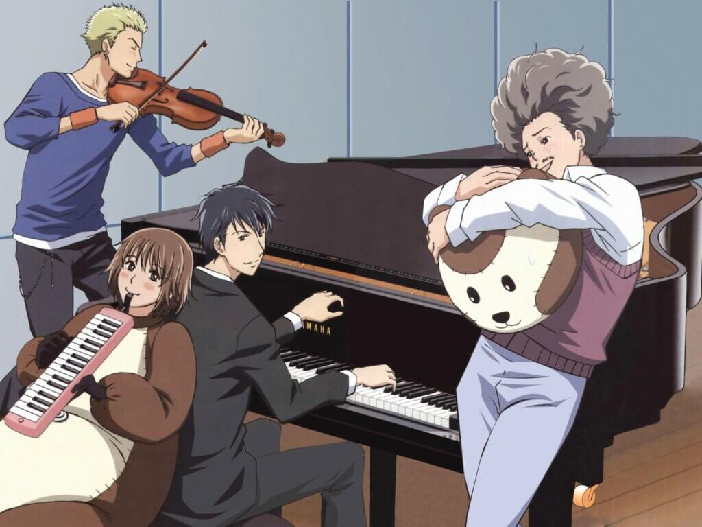 Image is the cast of Nodame Cantible, a black haired young man playing piano (Chiaki), a brunette girl in a bear suit playing a melodica (Nodame), a blonde guy in a blue sweater playing a violin (Ryutaro), and a fluffy haired man with a mustache wearing a sweater and jeans while holding a mascot bear head.