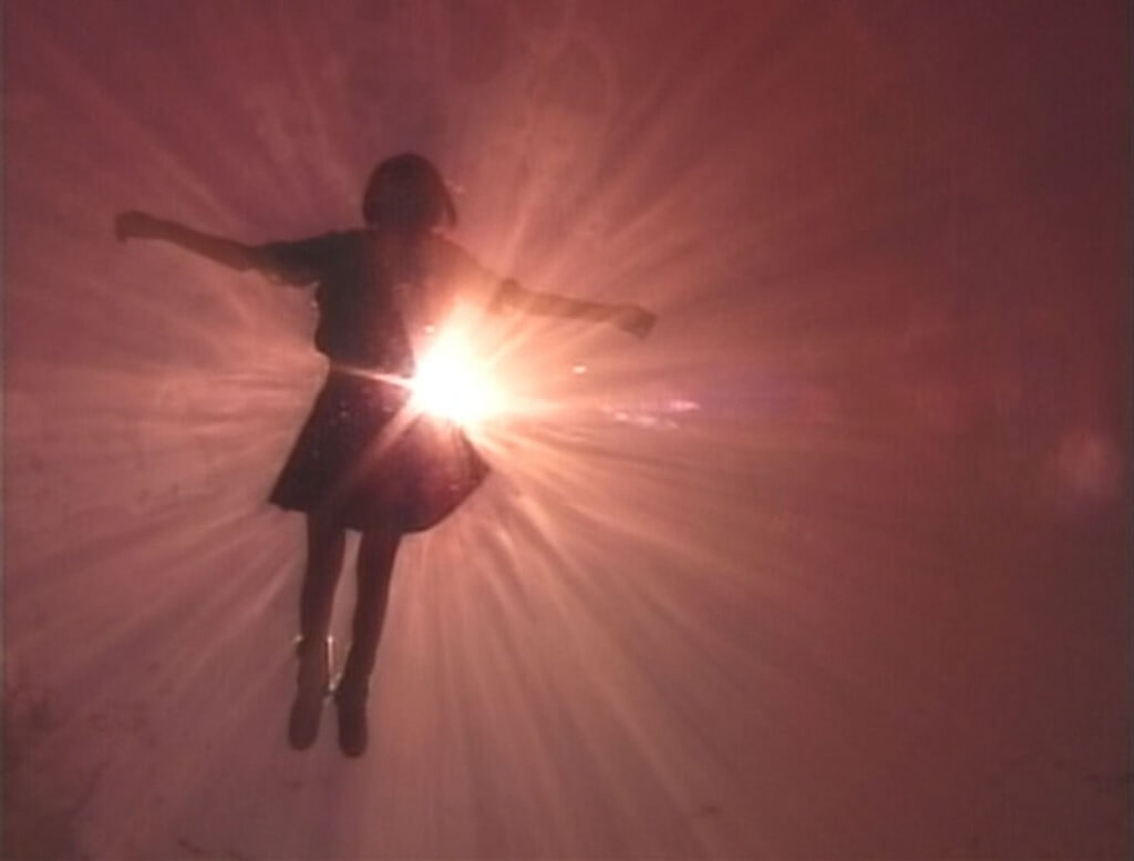 Hiromi floats in water. The sun shines on her from overhead.