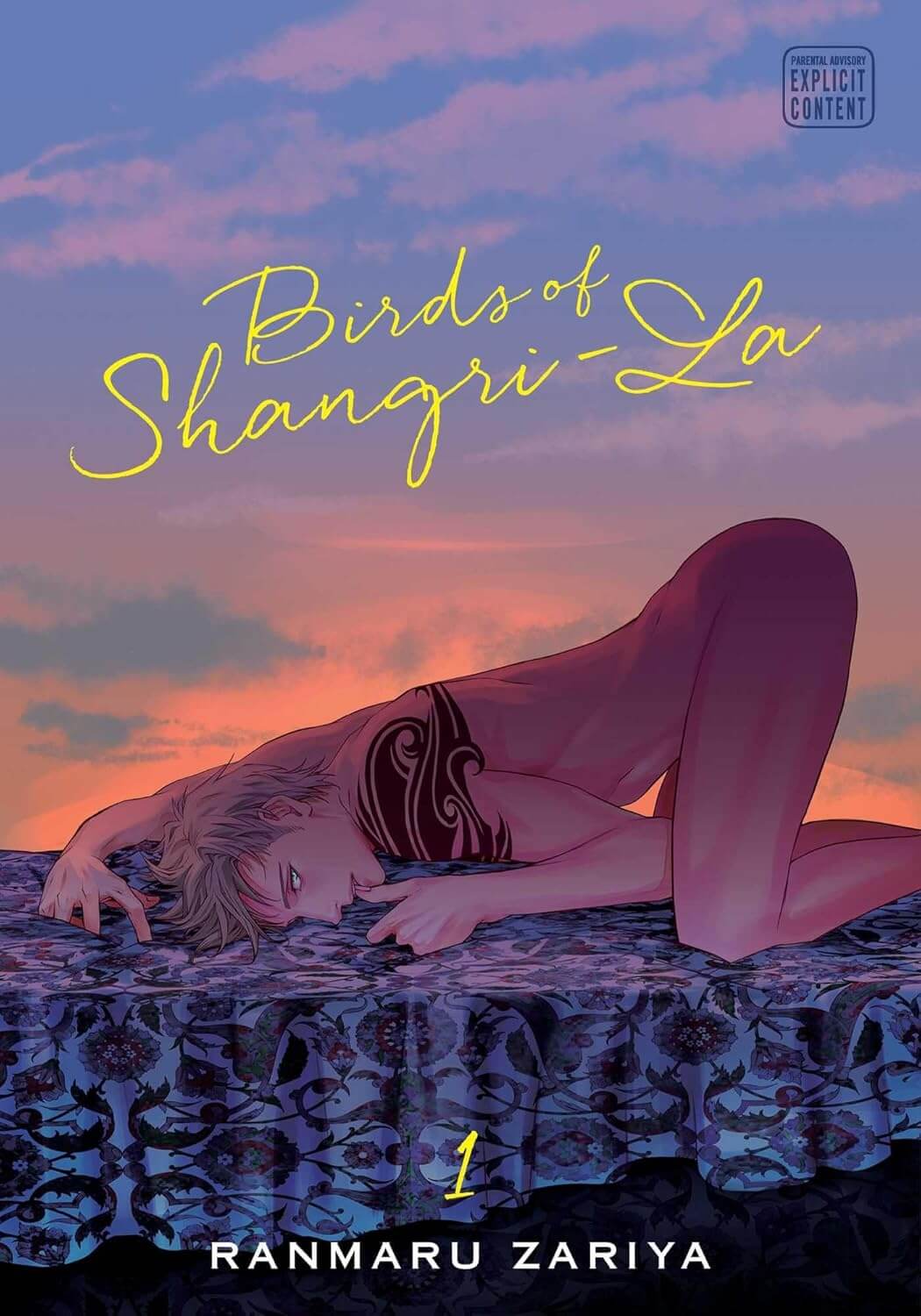  Birds of Shangri-la Volume 1. A young blonde man with a fake tribal tattoo lays on his hands and knees on a bed with a flower-patterned sheet on top. He has his back bent in an arch with his bottom in the air. He grips the sheet with one hand and sucks on his thumb with the other. In the background is a beautiful pink and blue sunset