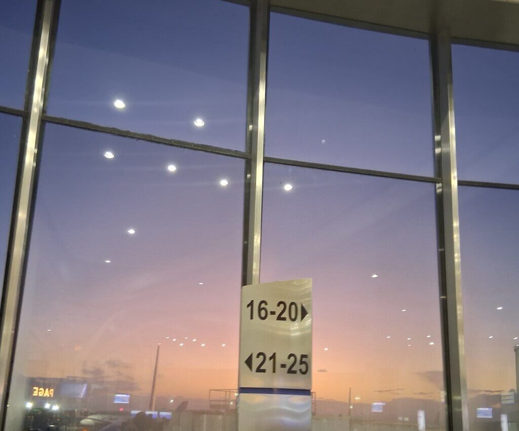 the airport windows at Washington-Reagan airport, which show a grey-orange sky and reflecting the airport lights
