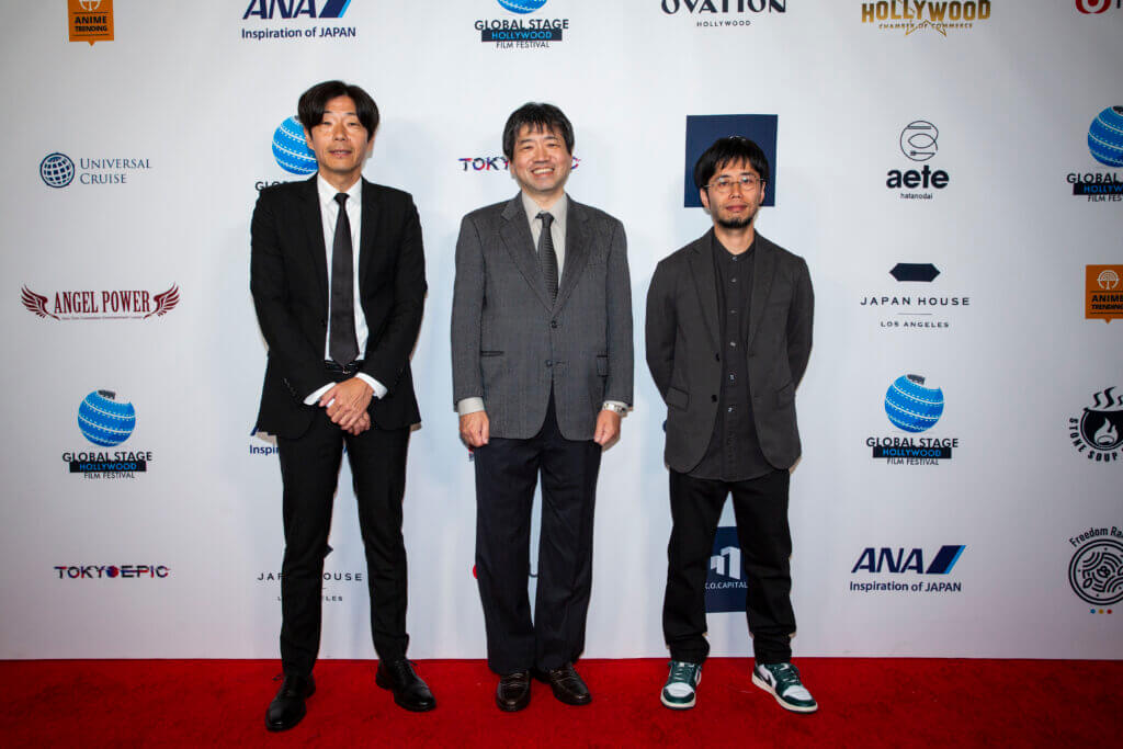 Producer Ryo Oyama, Director Nobuyuki Takeuchi, and Director Seichiro Nagaya before the Tatsuki Fujimoto 17-26 screening. Oyama and Takeuchi are wearing suits. Nagaya is wearing a sports coat with a button-up and sneakers.