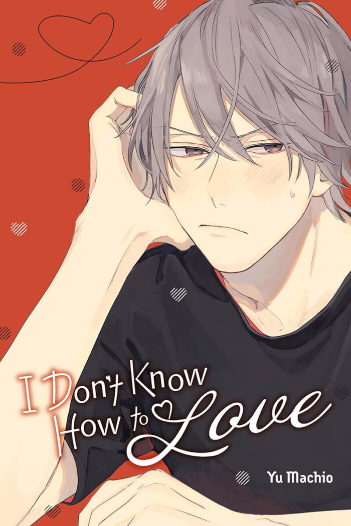 I Don’t Know How to Love by Yu Machio cover featuring Aimi, a cool college student propping his head up with one hand while blushing. He is frowning as if confused, and the background is covered in little heart motifs.
