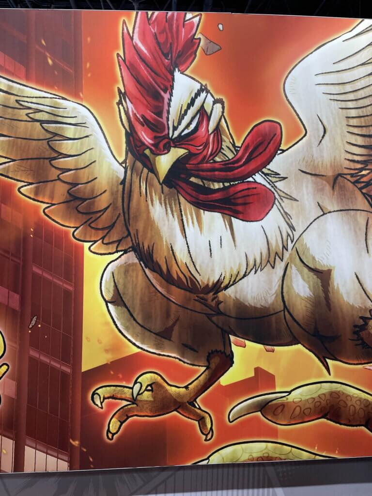 A stand promoting Rooster Fighter. A rooster with a determined expression on its face gets ready to fight. Behind it are burning buildings.