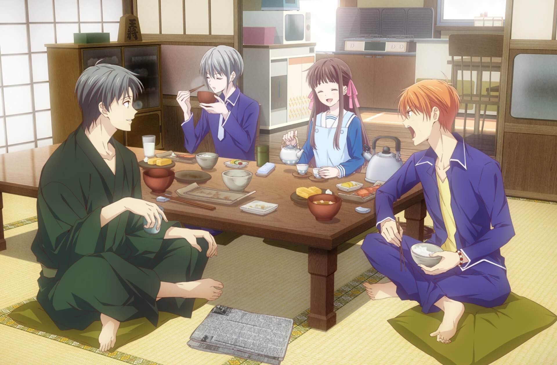Shigure, Tohru, Kyo and Yuki sit on cushions around a low table in a traditional japanese style house, eating dinner. Kyo is shouting at Yuki who is staying cool and calm, whilst Tohru smiles goofily and Shigure enjoys the show. Shigure is in a green kimono and has black hair. Yuki has grey hair and is wearing a blue highschool uniform, Kyo has orange hair, and the same uniform except the shirt is open to reveal a yellow t-shirt and the tie is abandoned. Tohru has long brown hair tied up with pink ribbons, she wears an apron over her uniform.