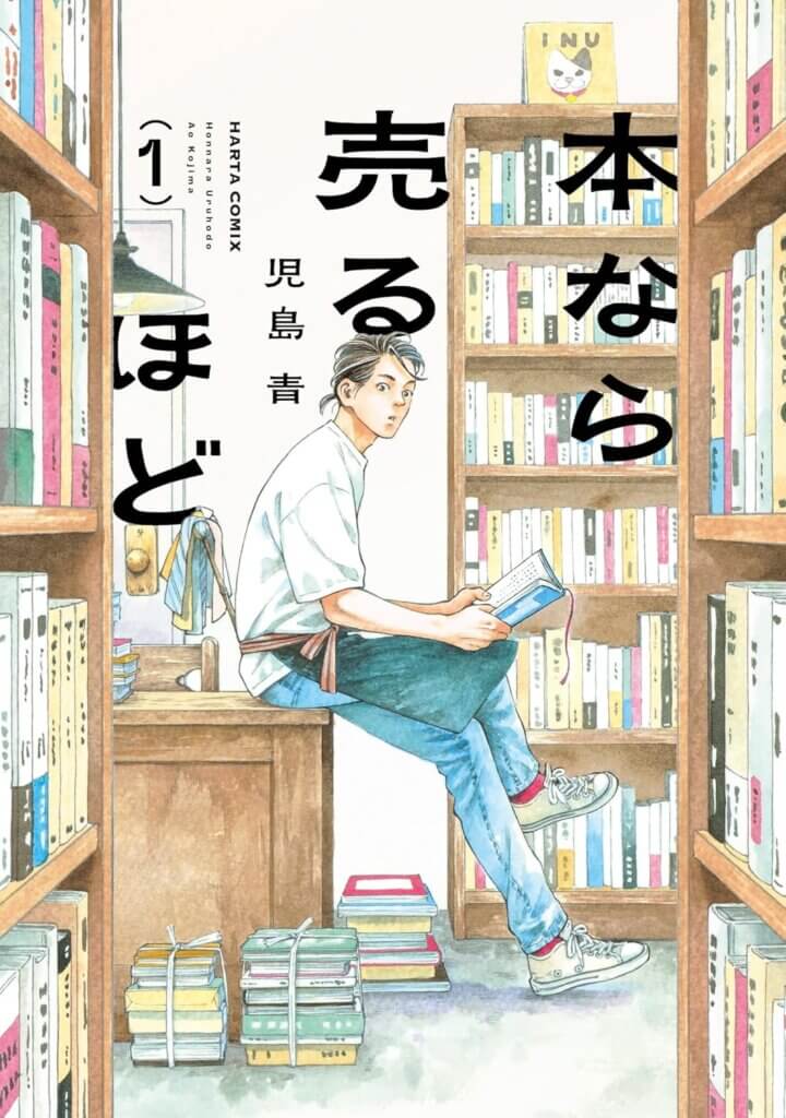 The cover of the manga series Hon Nara Uru Hodo, depicting a man with a ponytail sitting on a table. He is surrounded by bookshelves and tied-up books.