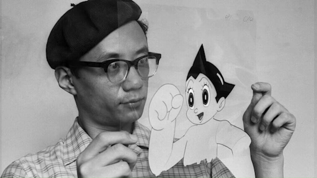 An image of Osamu Tezuka holding up a cell of his hero Atom, from Astro Boy.